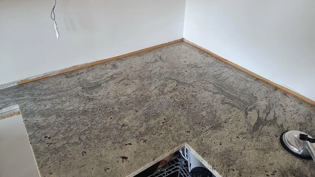 L-format hörn av köksbänk i polerad Antique White-granit med levande ådring i grått och brunt, Frillesås.