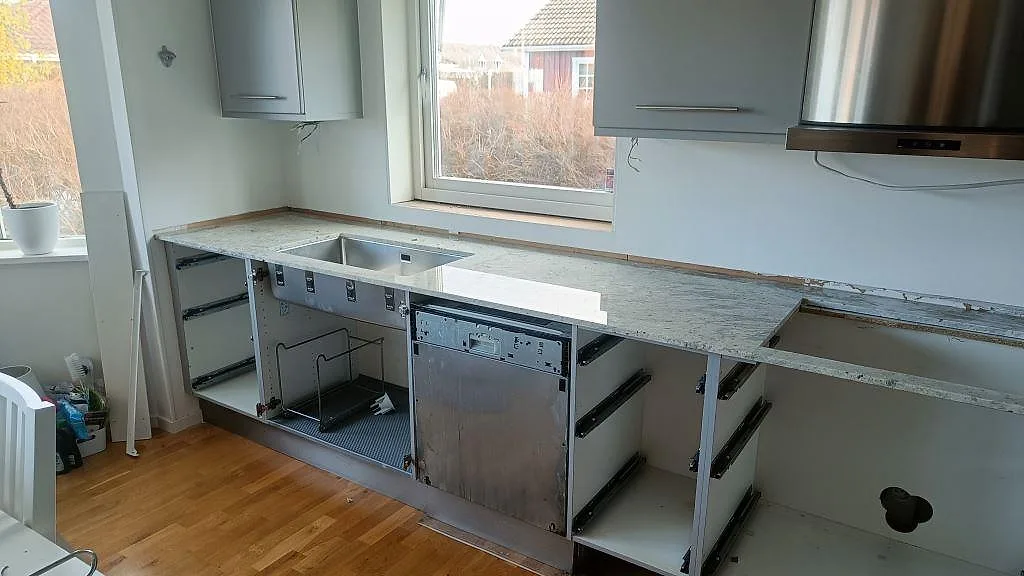 Köksbänkskiva i vit granit Antique White, polerad, med underlimmad rostfri diskho i ett kök under montering i Frillesås.