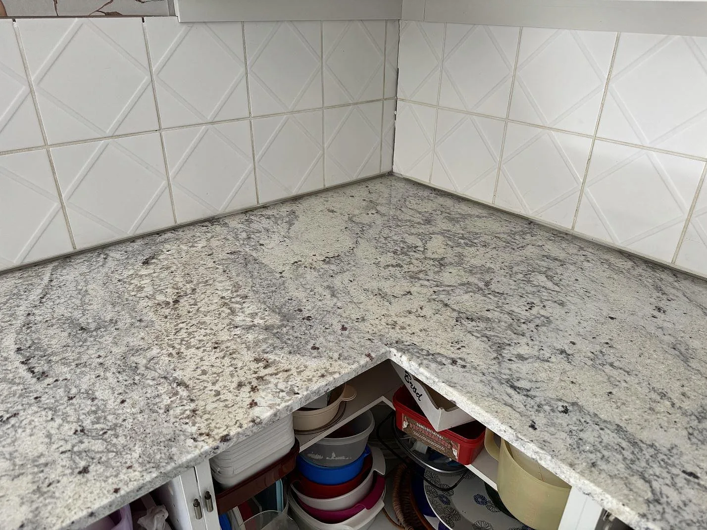 Invändigt hörn med polerad Antique White granit och vit kakelvägg i kök i Gärds Köpinge.