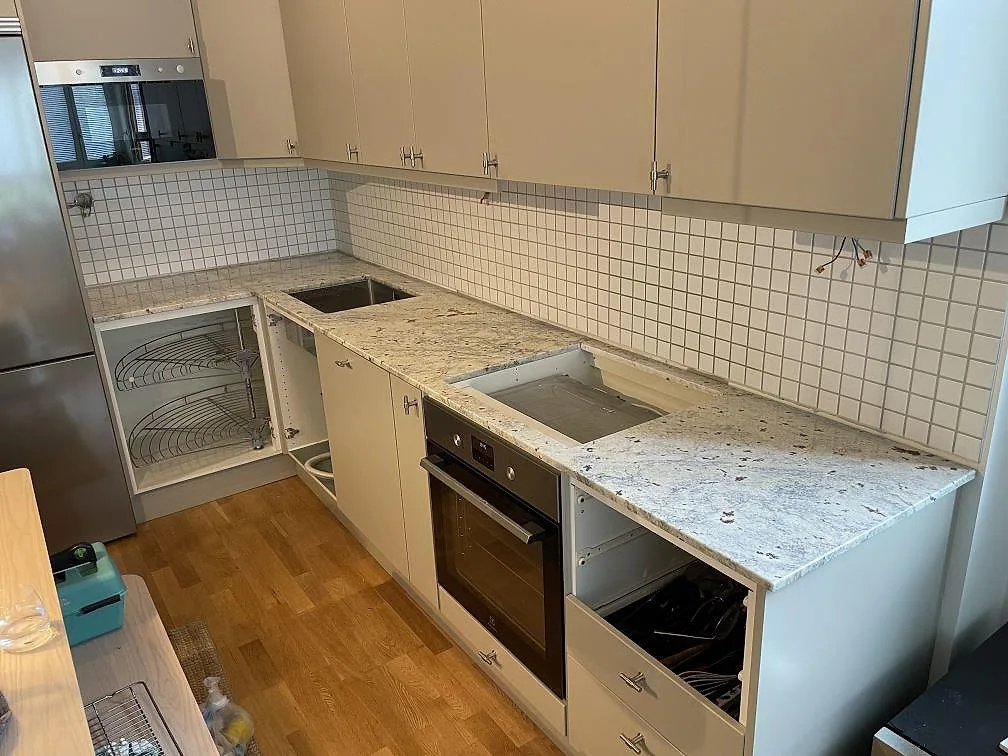 Köksbänkskiva i polerad Antique White granit, 20 mm, med öppningar för diskho och häll i ett kök i Hägersten under montering.