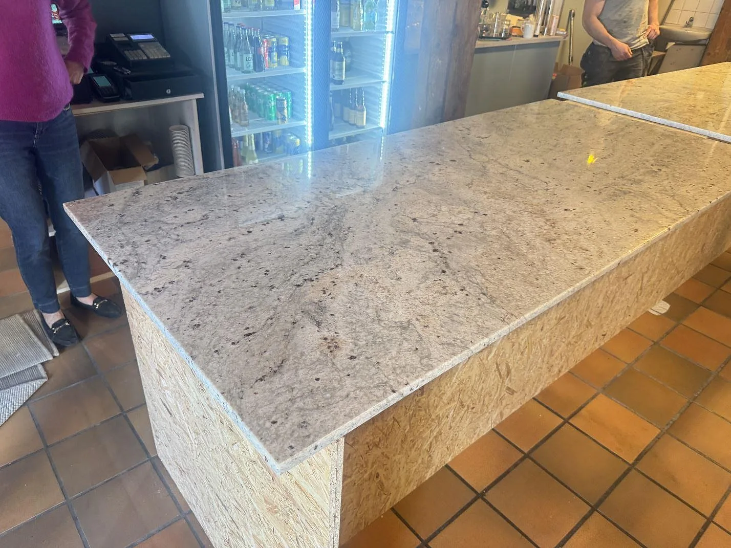 Serveringsdisk i 20 mm polerad Antique White granit i en kommersiell miljö i Helsingborg, med ljus stenyta över en OSB-klädd disk.