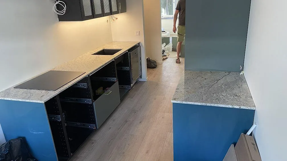 Köksbänkskiva i polerad Antique White granit med häll och diskho i ett kök under montering i Helsingborg.