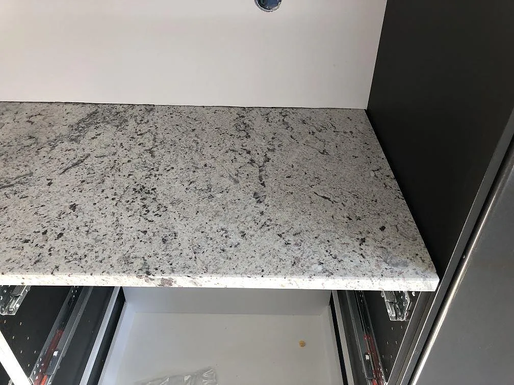 Underlimmad rostfri diskho i vit Antique White granit med svart och grå ådring på köksbänkskiva i Hindås.