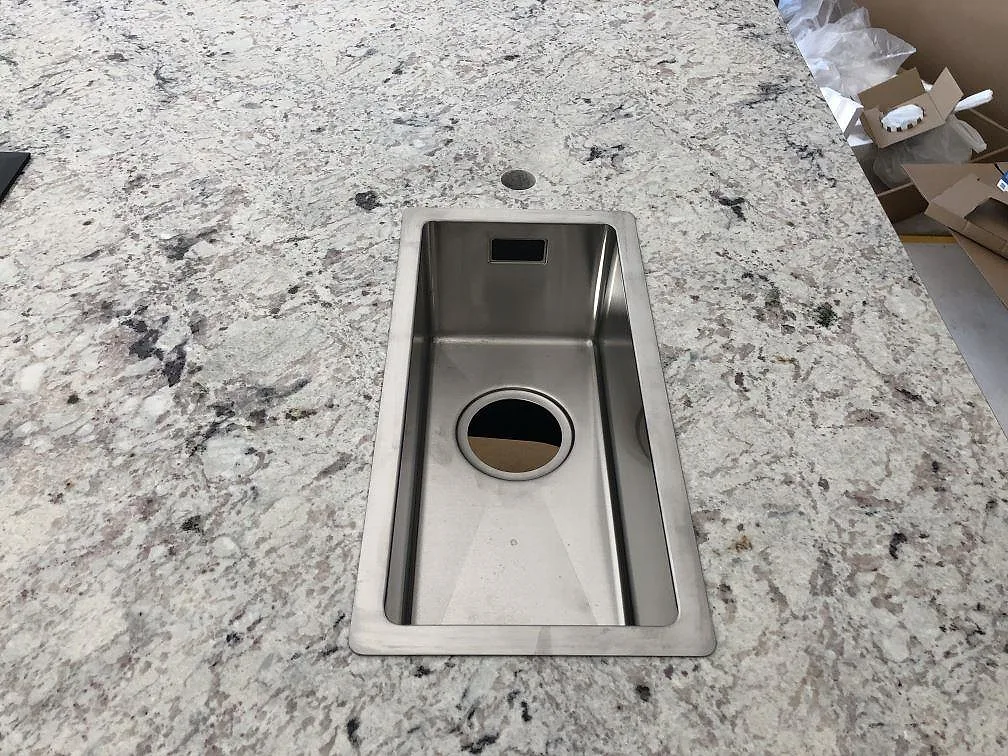 Köksö i vit spräcklig Antique White granit med infälld induktionshäll, polerad yta, sedd uppifrån i ett kök i Hindås.