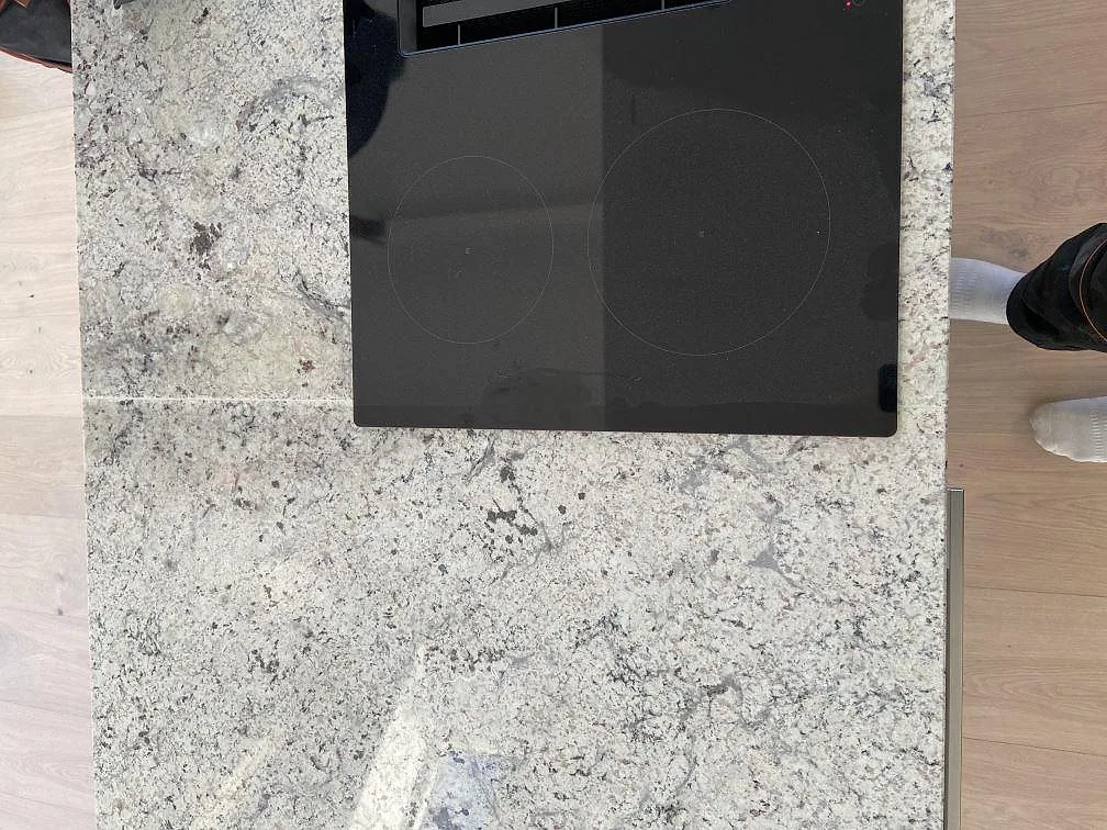 Övermonterad Siemens induktionshäll på polerad Antique White granitbänkskiva i ett kök i Höllviken.