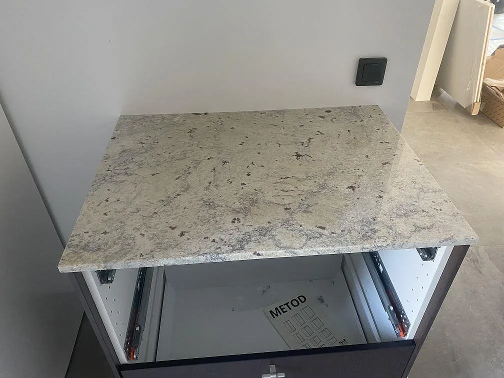Rak arbetsyta i polerad Antique White granit monterad på träinredning i en tvättstuga i Höllviken.