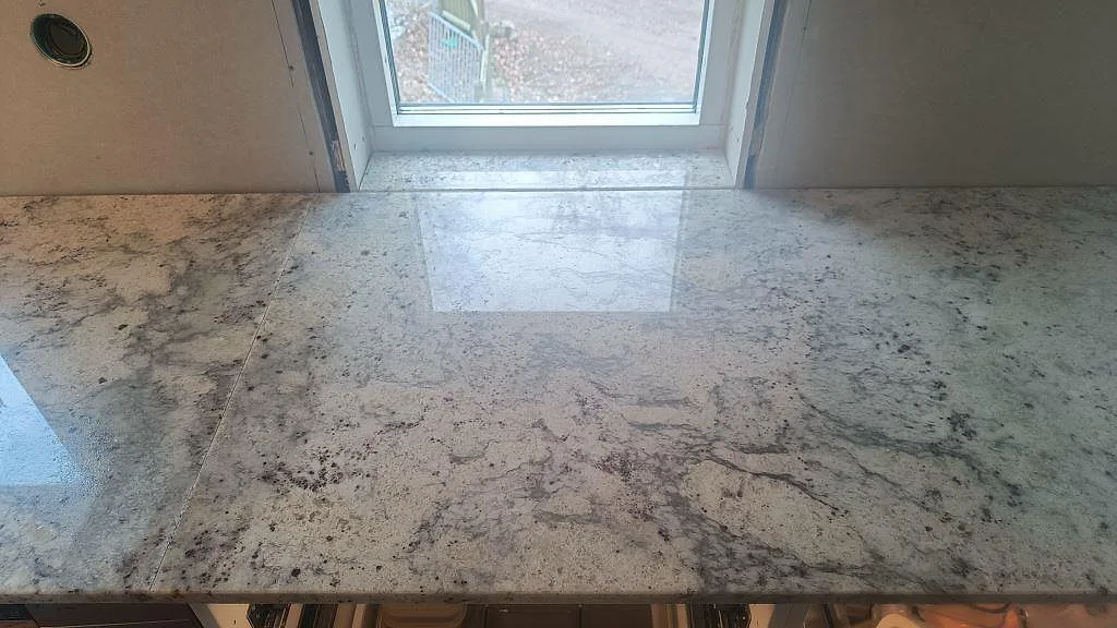 Topvy av polerad Antique White-granit med blank yta och ådring under fönster i Hörby.