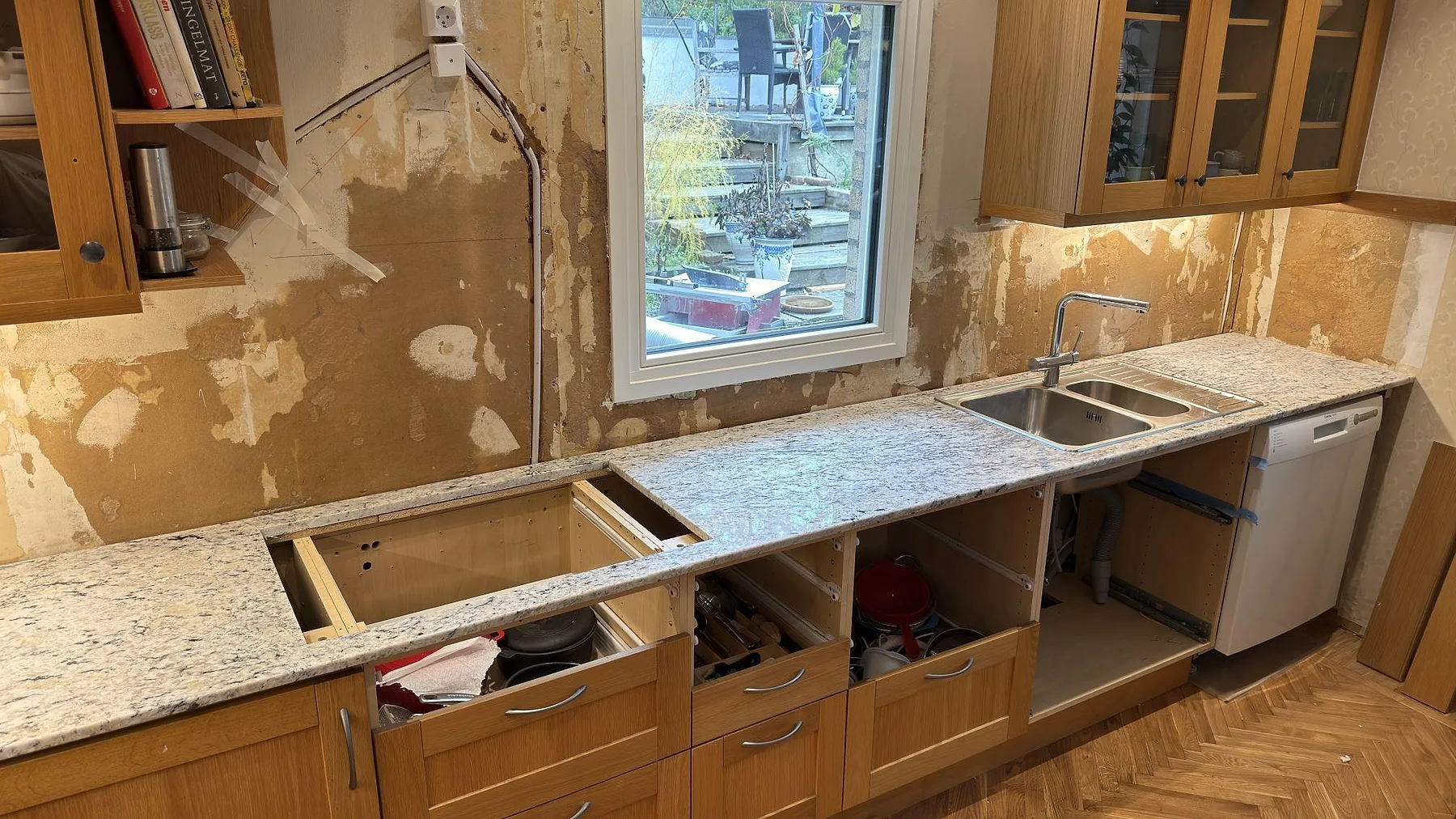 Närbild av polerad Antique White granit som köksbänkskiva i Huddinge, med hällöppning och diskho under pågående montering.
