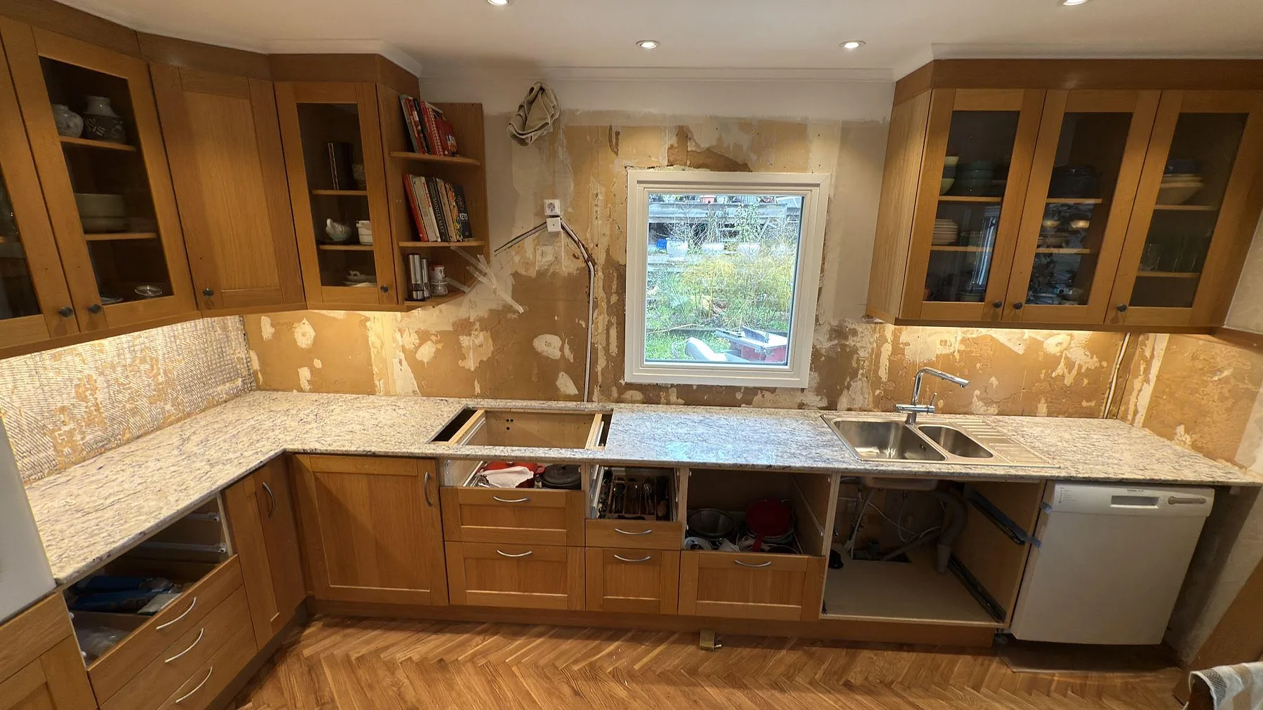 Köksbänkskiva i polerad Antique White granit i ett kök i Huddinge, med hällöppning, diskho och ljus stenådring under montering.