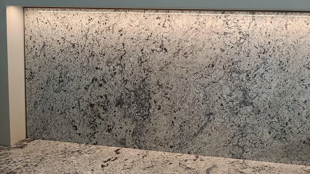 Närbild på ådringen i den bakbelysta stänkväggen av Antique White-granit i Kungsbacka.