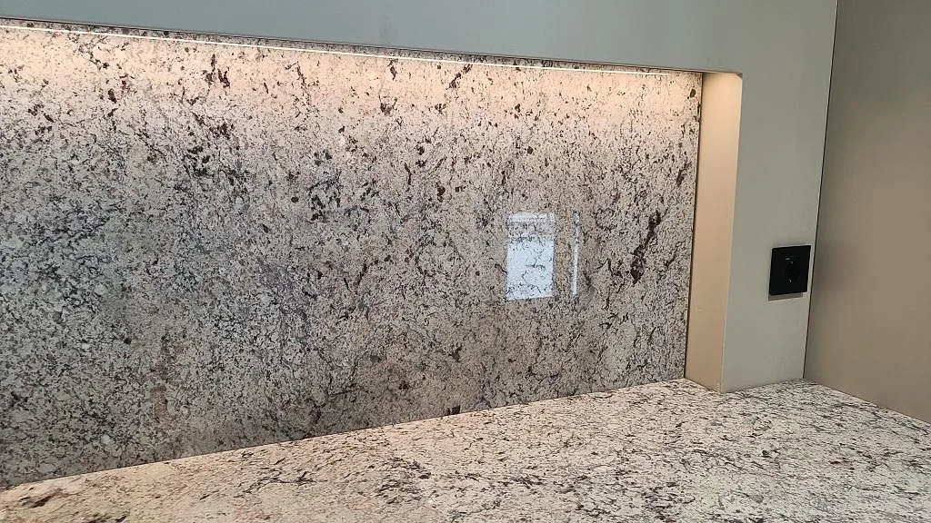 Stänkvägg och bänkskiva i vit Antique White-granit i ett kök i Kungsbacka.