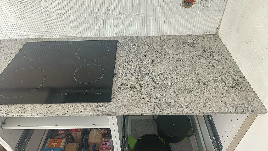 Polerad köksbänkskiva i Antique White granit med spräcklig grå ådring på köksö i ett kök i Landskrona.