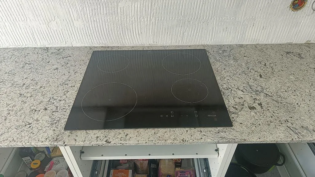 Infälld induktionshäll i Antique White granit köksbänkskiva med grå och svart spräcklig ådring i Landskrona.