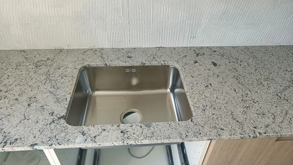 Köksbänkskiva i Antique White granit med underlimmad rostfri diskho i ett kök i Landskrona.