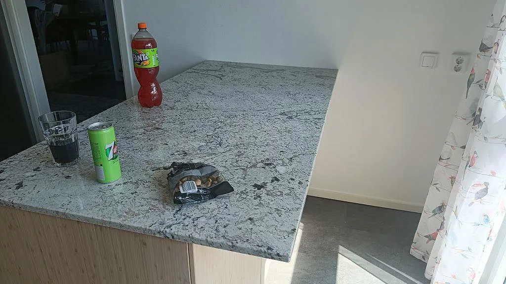Antique White granit köksbänkskiva i hörn med underlimmad rostfri diskho och bara väggar under montering i Landskrona.