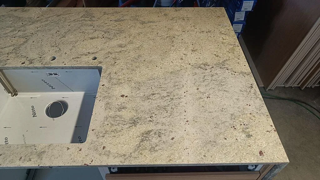Naturlig grå ådring och rostbruna prickar i den polerade Antique White-graniten till köket i Ljungbyhed.