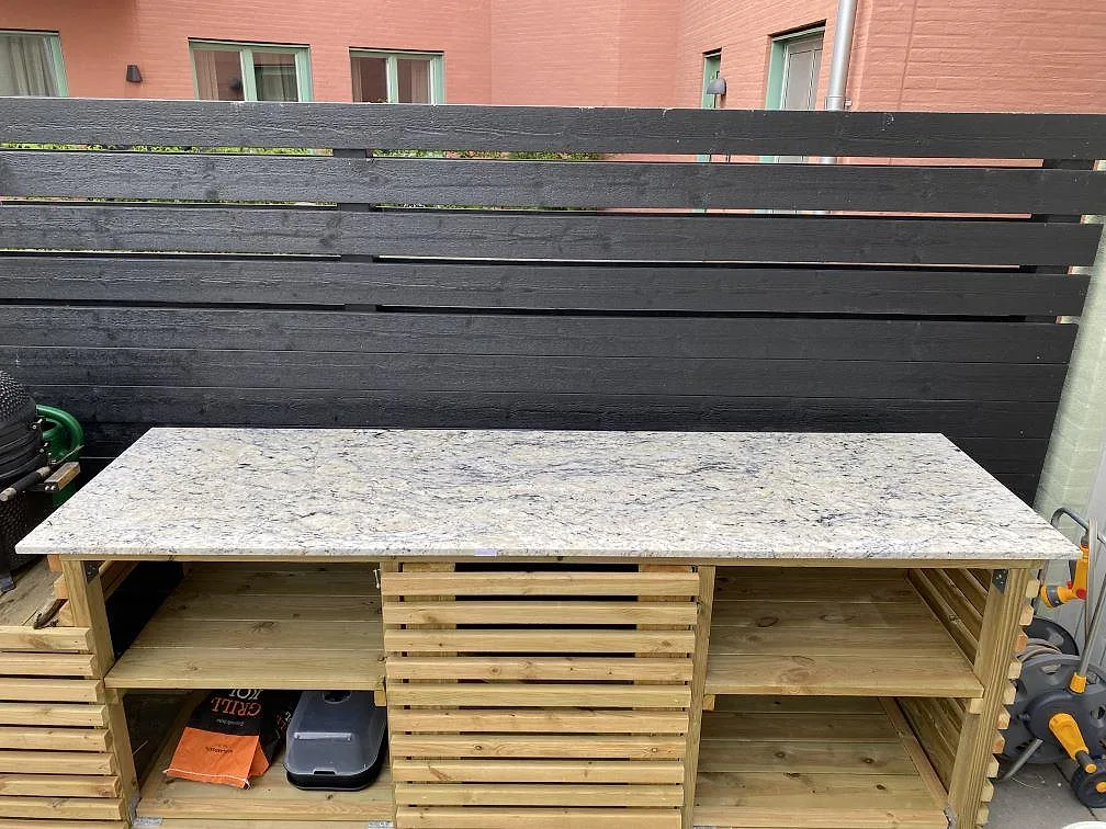Bänkskiva i Antique White granit, polerad, på en platsbyggd träbänk utomhus i Lomma.