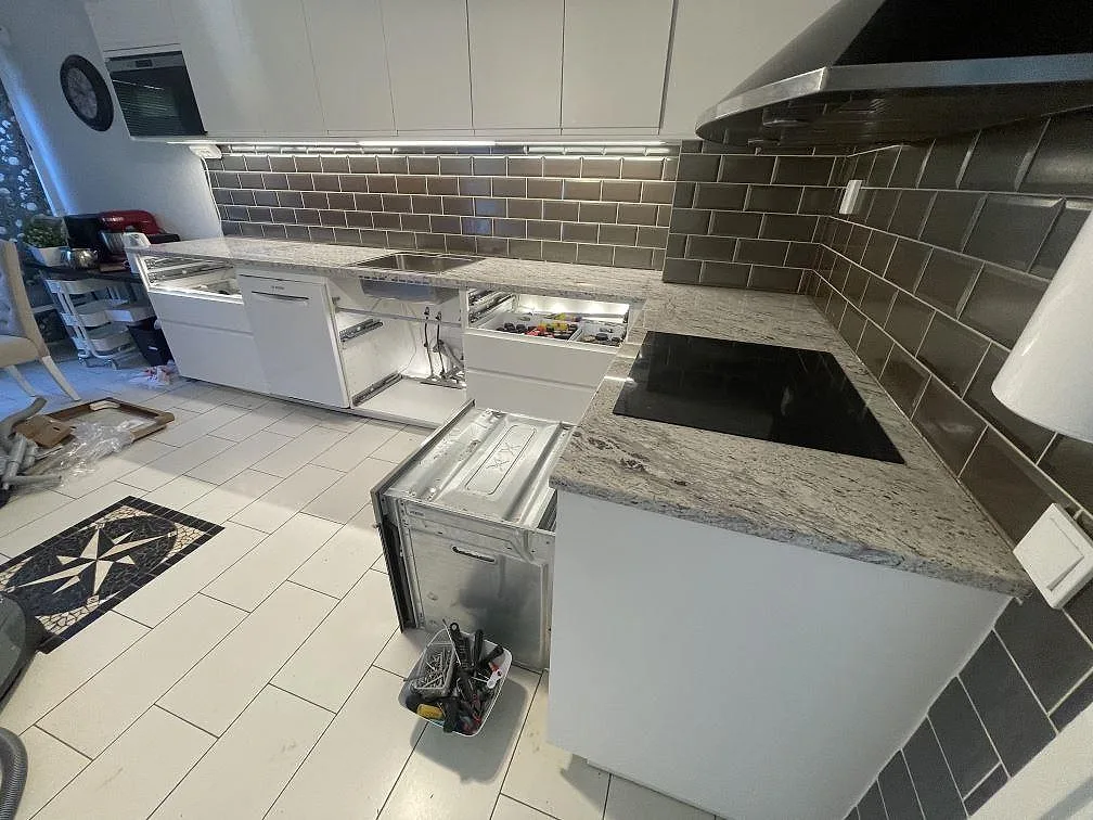 Köksbänkskiva i polerad Antique White granit med induktionshäll, diskho och vit köksinredning under montering i Malmö.