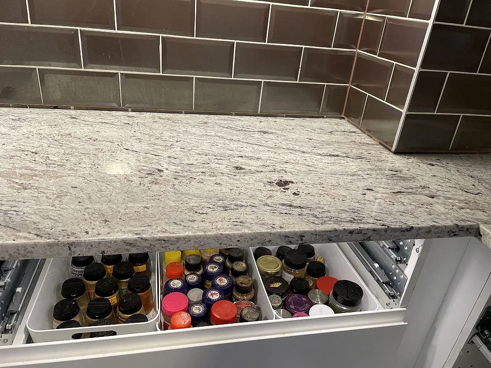Yta och ådring i polerad Antique White granit på köksbänkskiva med öppna kökslådor i Malmö.