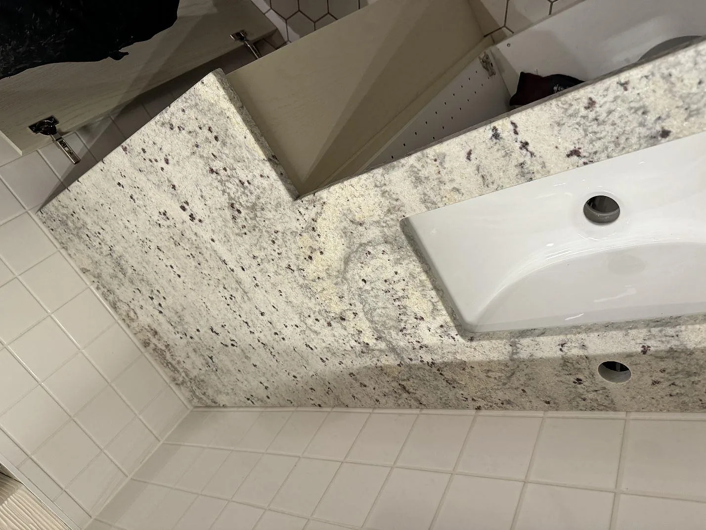 Detalj av matt Antique White granit runt tvättställ och blandarhål i badrum i Malmö.