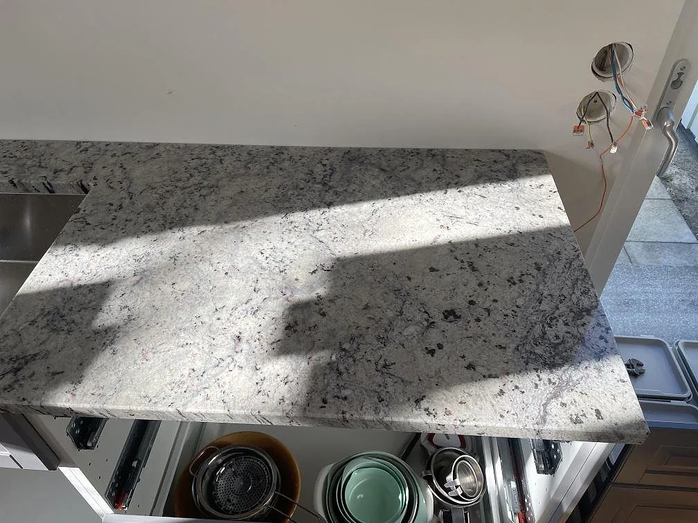 Köksbänkskiva i Antique White granit i solljus, polerad yta, i ett kök i Skanör.
