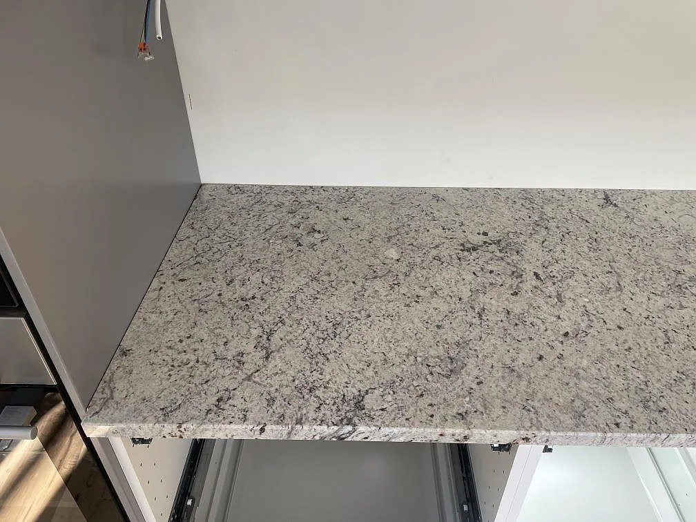 Installerad köksbänkskiva i Antique White granit, polerad, längs köksväggen i Skanör under montering.