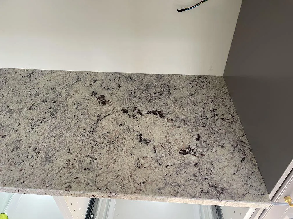 Polerad köksbänkskiva i Antique White granit med tydlig kornig ådring och granatstänk i ett kök i Skanör.