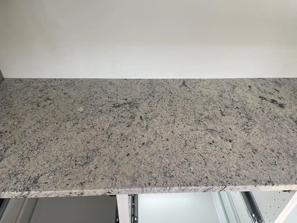Köksbänkskiva i Antique White granit, polerad yta med grå och beige ådring, monterad i ett kök i Skanör.