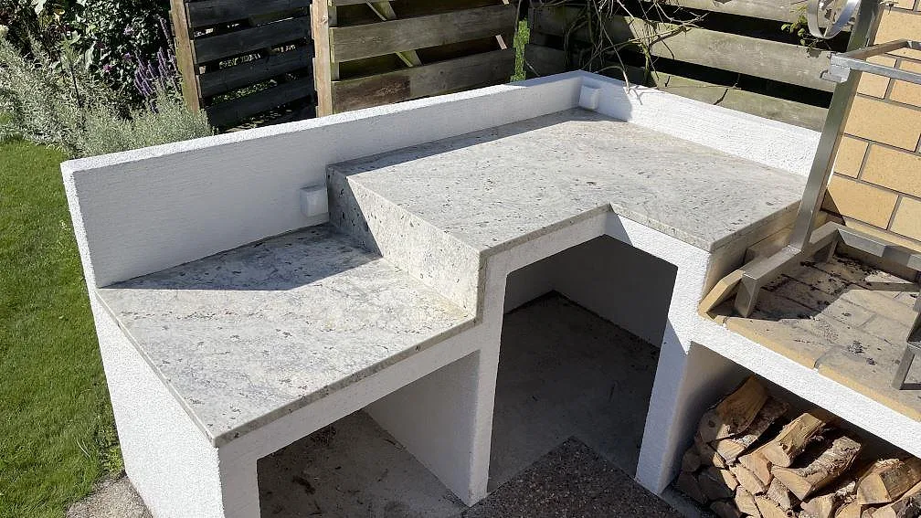 Matt köksbänkskiva i 30 mm Antique White granit som L-formad arbetsyta runt ett utekök i Skanör.