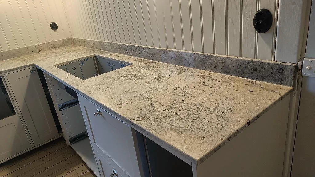 Polerad Antique White granit som bänkskiva med underlimmad diskho, stänkkant och vit köksinredning i Sölvesborg.