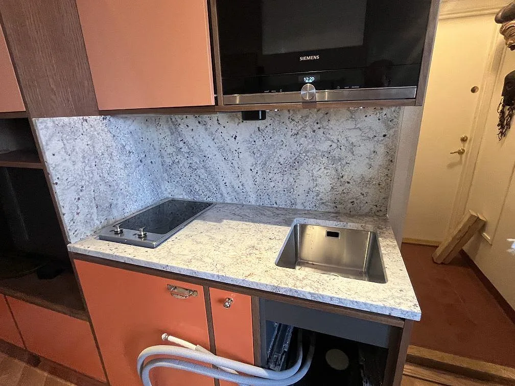 Köksbänkskiva i matt Antique White granit med underlimmad rostfri diskho, svart induktionshäll och heltäckande stänkskydd i Stockholm.