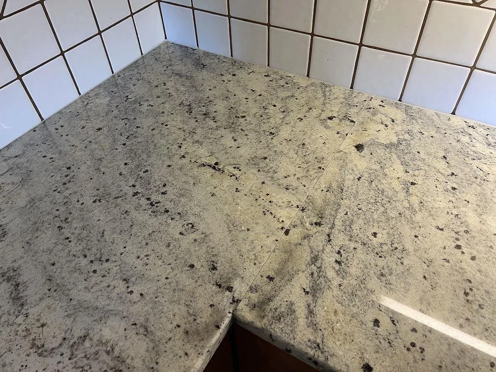 Hörndel av polerad Antique White granit med naturlig ådring i ett L-format kök i Svedala.