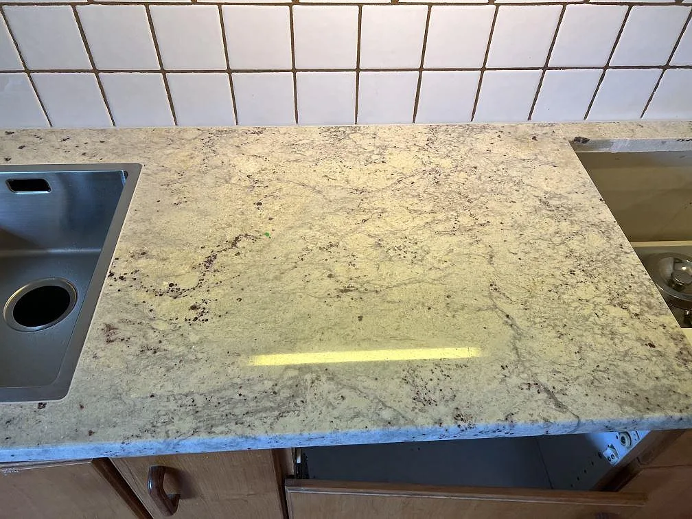 Polerad Antique White granit mellan dubbelho och hällurtag i ett kök med vitt kakel i Svedala.