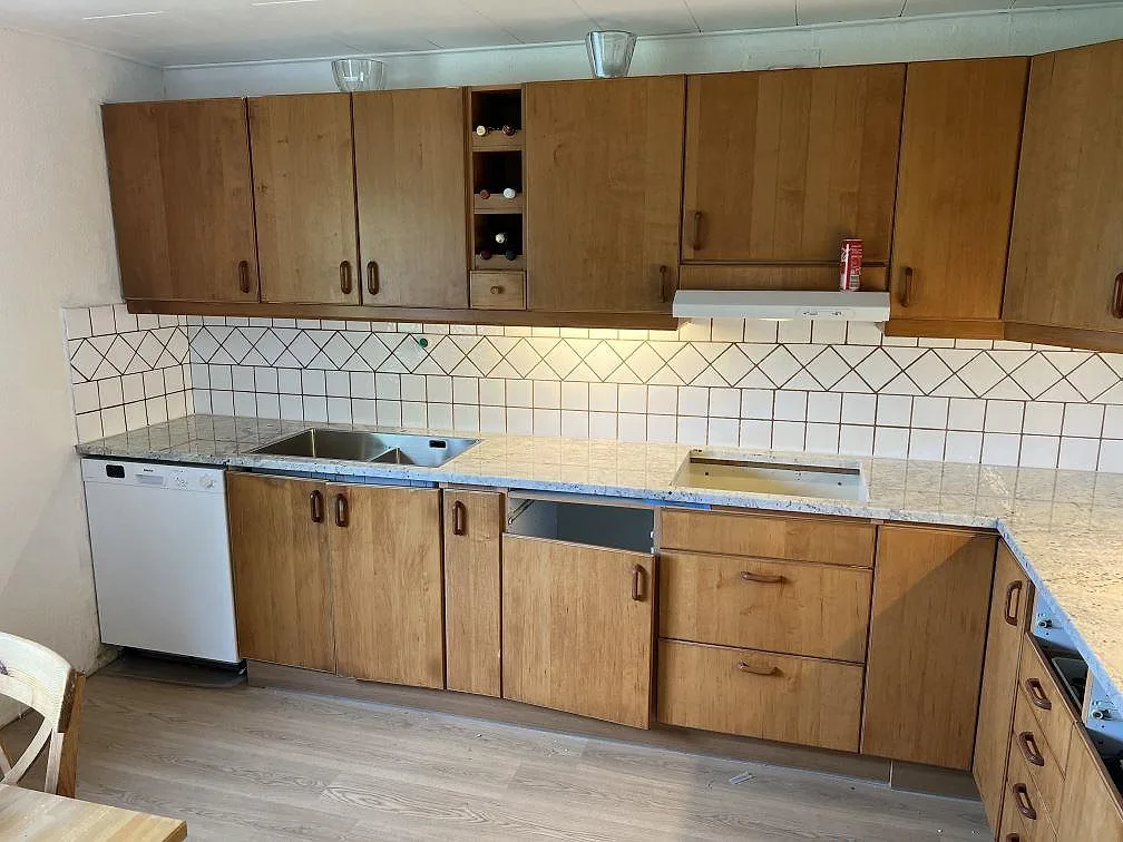 Köksbänkskiva i polerad Antique White granit med underlimmad rostfri dubbelho och hällurtag i ett kök i Svedala.