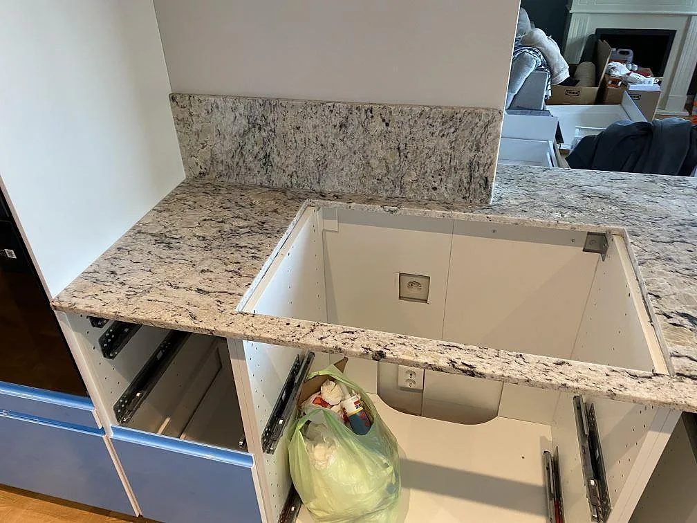Polerad Antique White granit som köksbänkskiva med uppvikt stänkkant och öppna stommar under montering i Svedala.
