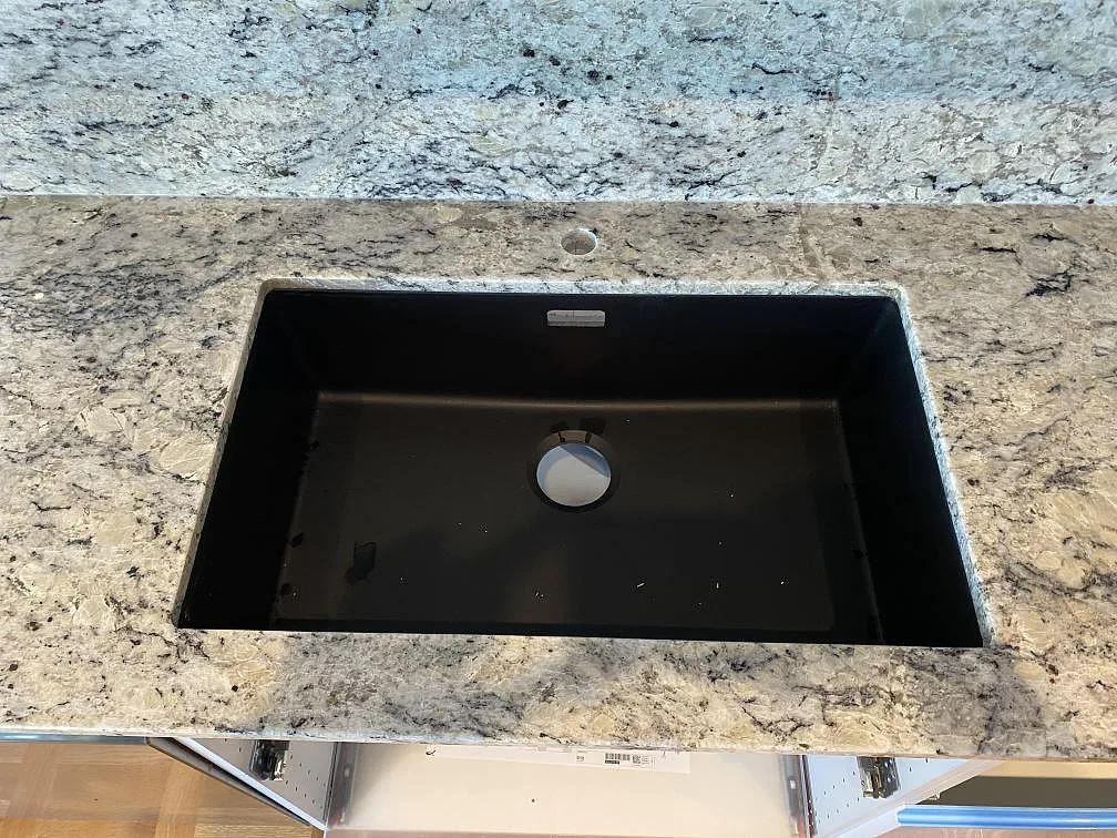 Svart diskho monterad under en polerad Antique White granitbänkskiva med stänkkant i Svedala.