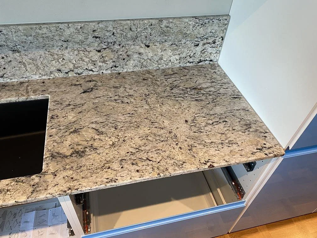 Arbetsyta i polerad Antique White granit med stänkkant och diskhozonen delvis synlig i Svedala.