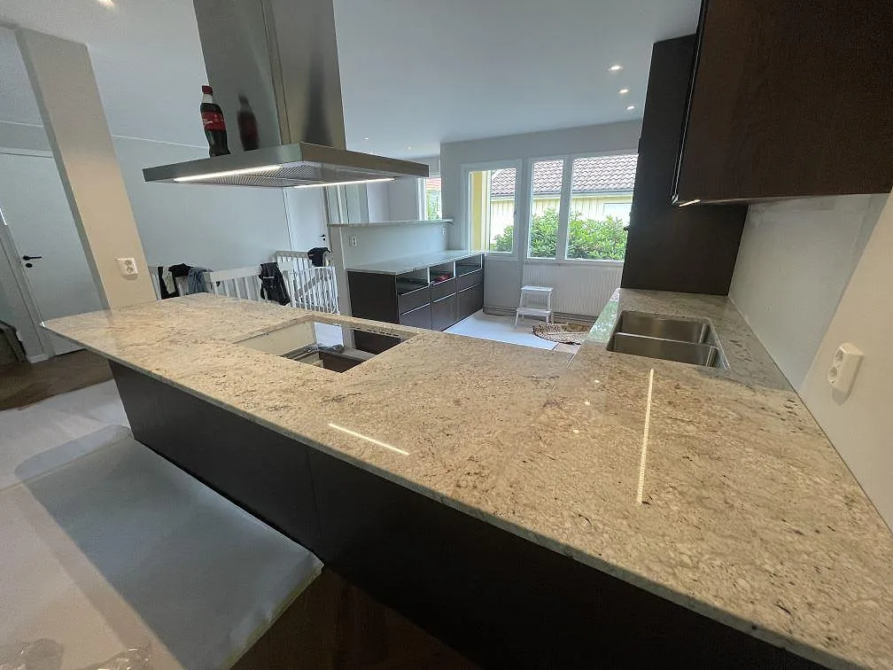 Köksbänkskiva i polerad Antique White granit, 30 mm, med hällöppning och synlig diskho i ett kök i Täby.