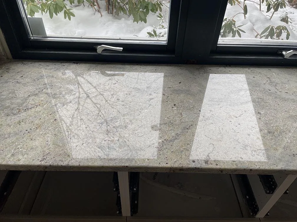 Polerad fönsterbänk i Antique White granit med grå ådring och granatstänk i ett kök i Trollhättan.