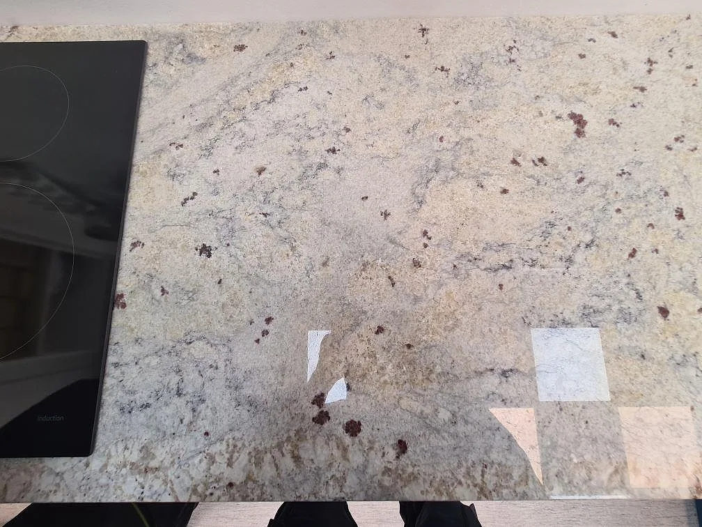 Detalj av polerad köksbänkskiva i Antique White granit med ljus yta, mörka prickar och hällkant i Uppsala.