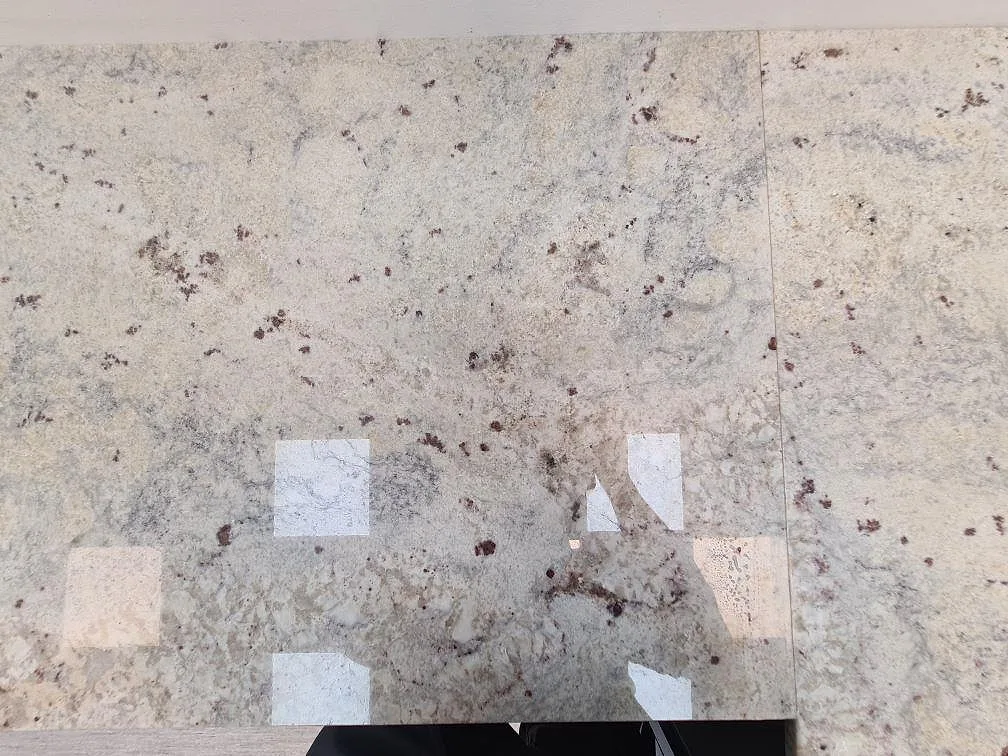 Polerad Antique White granit som köksbänkskiva med synlig skarv och speglingar från belysningen i Uppsala.