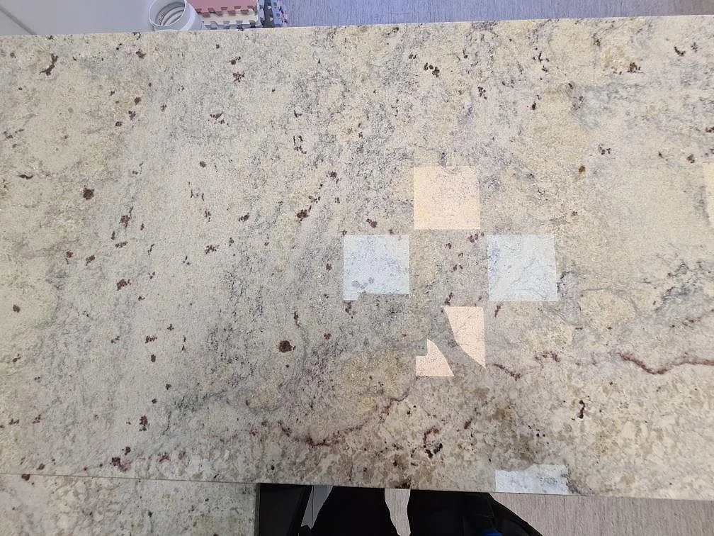 Detaljbild av ljus polerad Antique White granit med grå rörelser och mörkröda mineralinslag i köket i Uppsala.