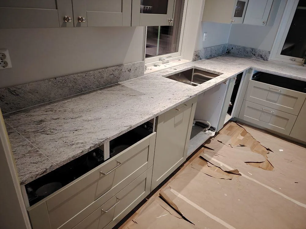 Matt Antique White granit som köksbänkskiva med synlig rostfri diskho, hällöppning och stänkkant i Västerås.