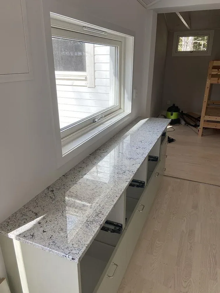 Köksbänkskiva och köksö i krämvit granit Antique White, polerad, i ett kök under montering i Växjö.