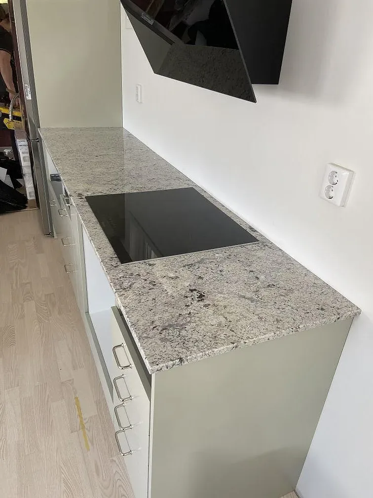 Köksbänkskiva i Antique White-granit med infälld induktionshäll i ett kök under montering i Växjö.