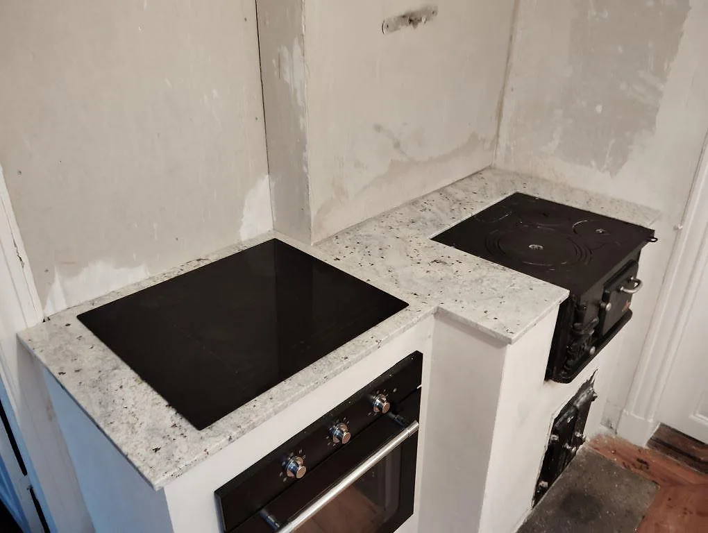 Köksbänkskiva i polerad Antique White granit, 20 mm, monterad runt spis och häll i ett kök i Vikbolandet.