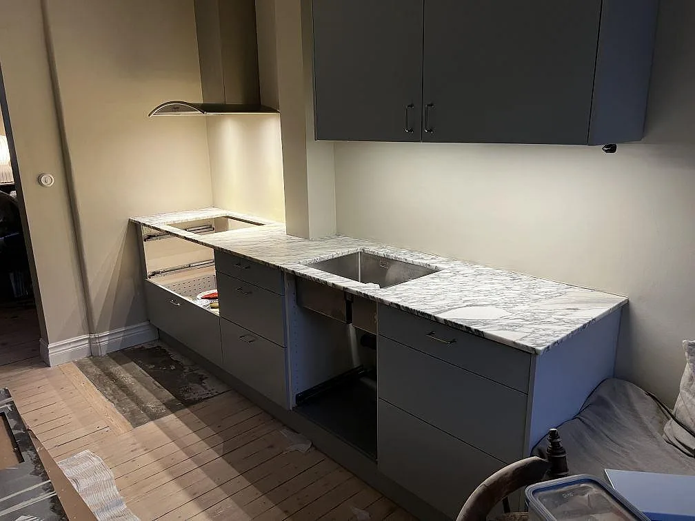 Köksbänkskiva i Arabescato marmor, matt, med rostfri dubbelho och hällöppning i ett kök i Göteborg.