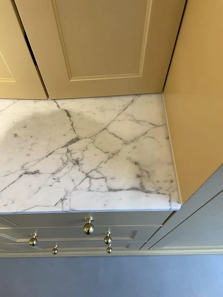 Detalj av matt Arabescato-marmor i 20 mm vid skåpsida och front, monterad som bänkskiva i Stockholm.