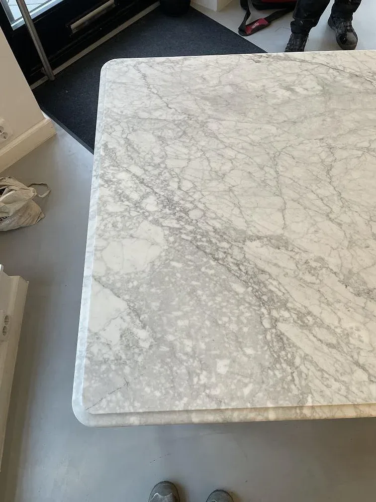 Närbild uppifrån av matt Arabescato-marmor med rundad kant och tät grå ådring på en bänkskiva i Stockholm.