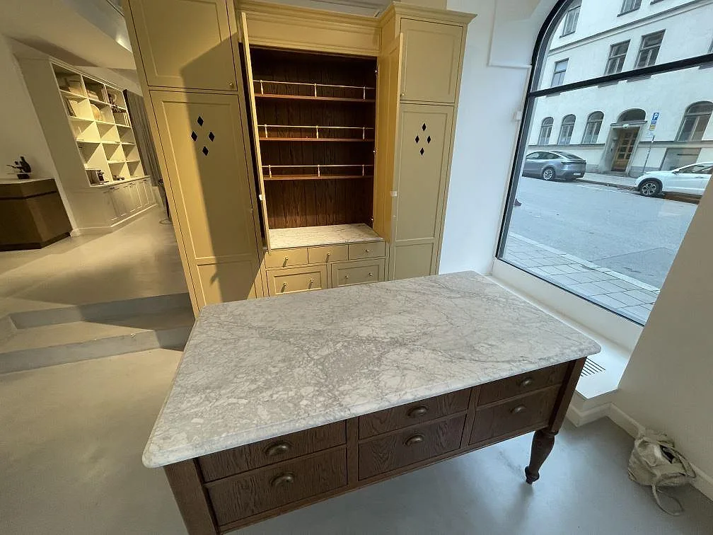 Matt bänkskiva i Arabescato-marmor på en fristående träinredning vid ett fönster i Stockholm.